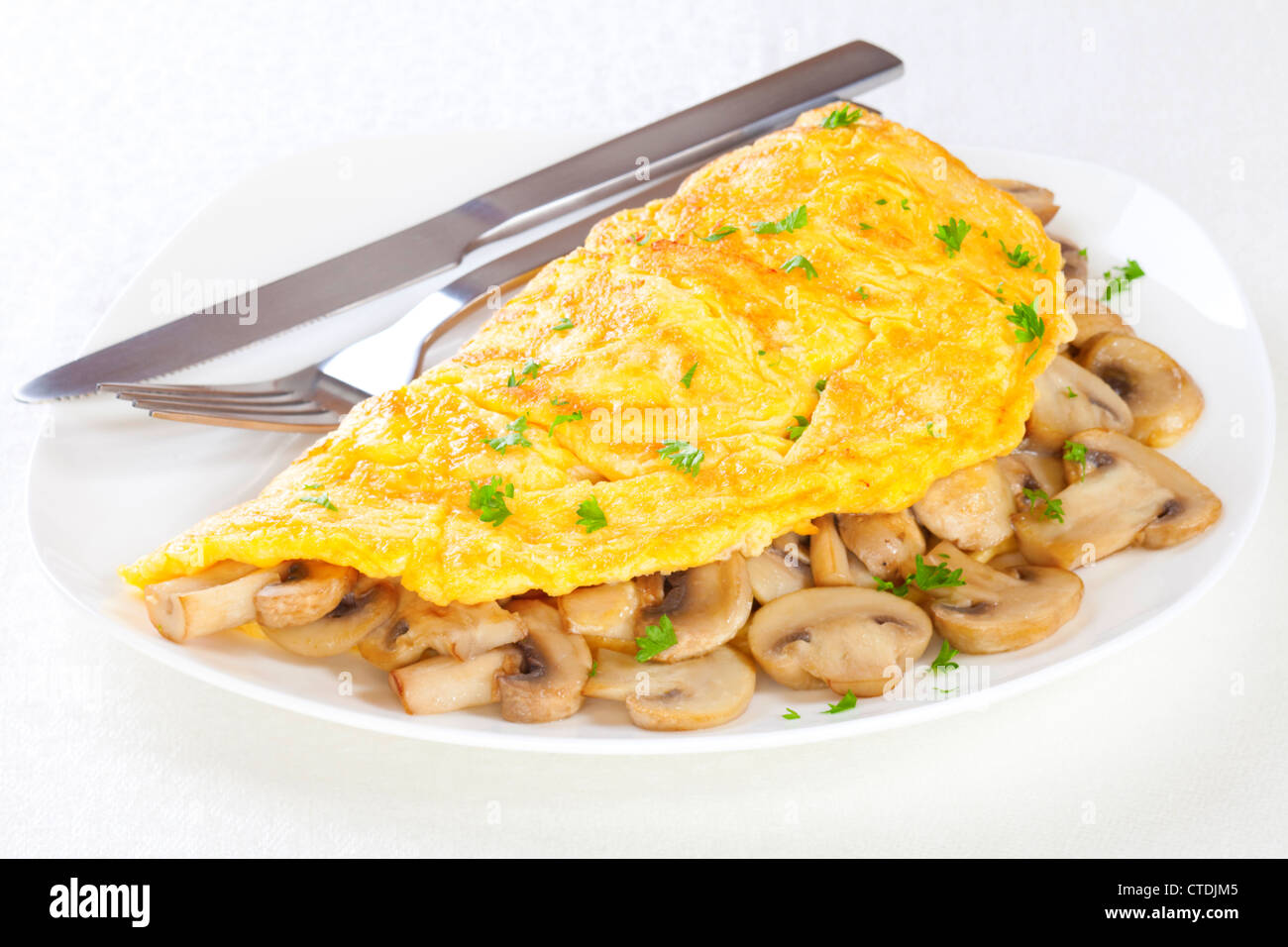 French omelet with mushrooms, on a plate and ready to eat. Stock Photo