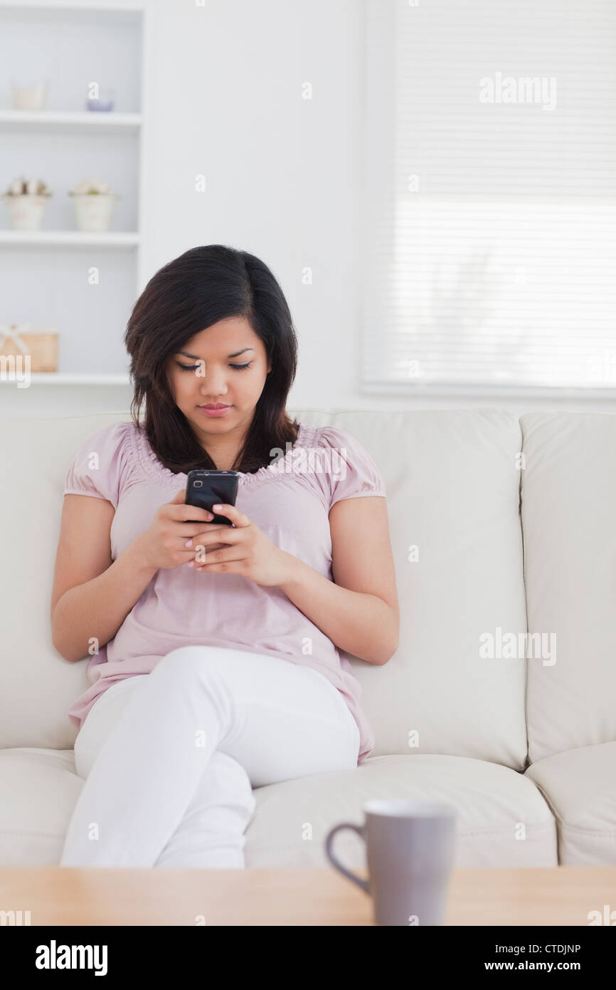 Woman sitting on a sofa while holding a phone Stock Photo - Alamy