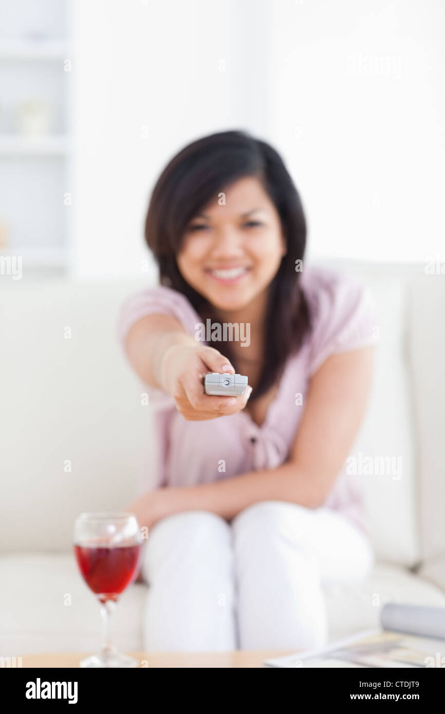 Blurred woman holding a television remote while sitting on a couch Stock Photo