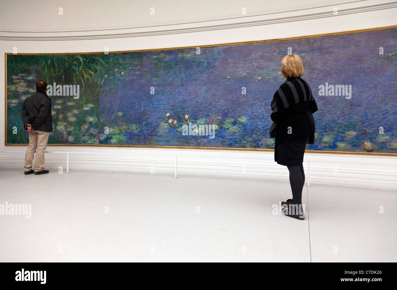 Visitors viewing one of eight water lilies murals housed in the Musee de l'Orangerie in Paris. Editorial use only. Stock Photo