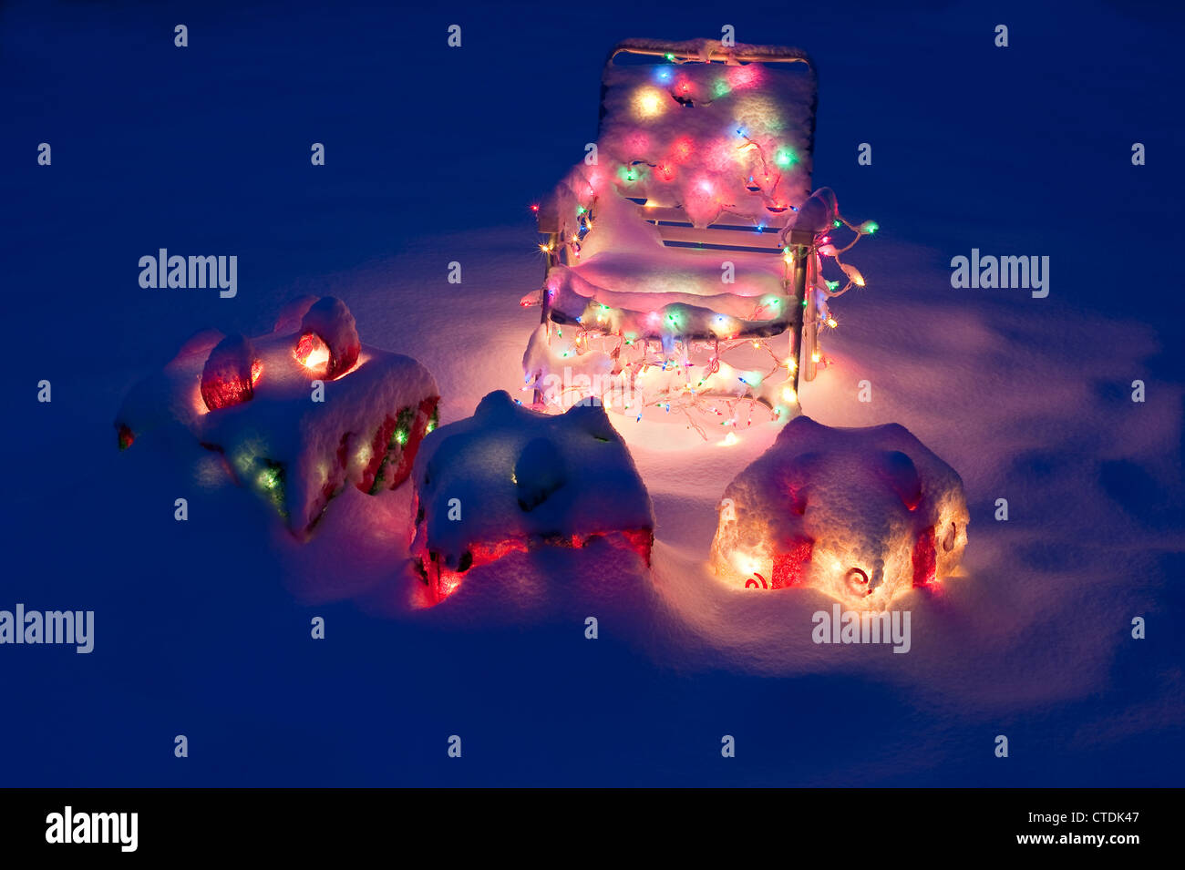 Decorated lawn chair with lit Christmas presents in snow covered backyard Stock Photo