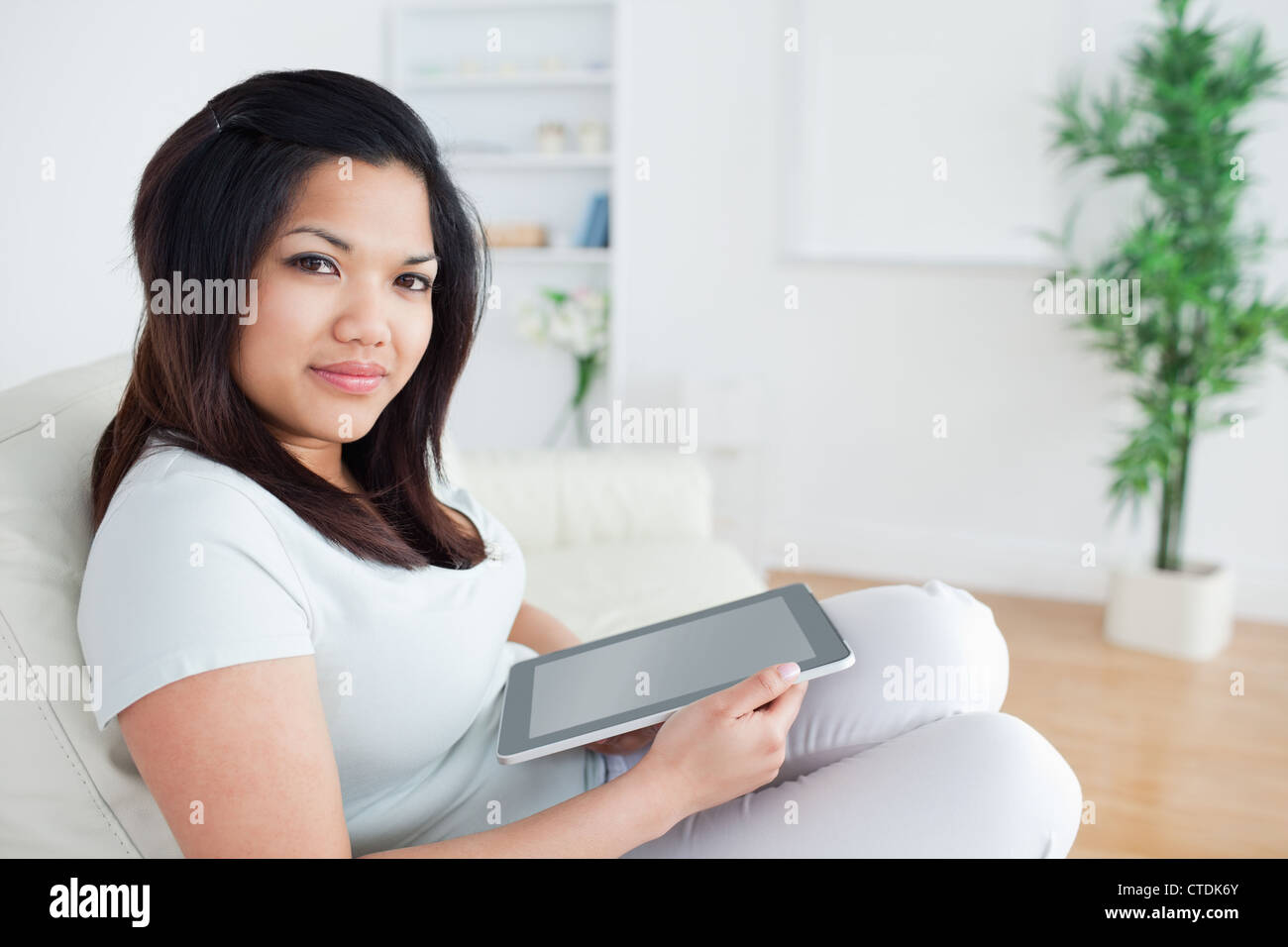 Woman sitting on a sofa while holding a tactile tablet Stock Photo - Alamy
