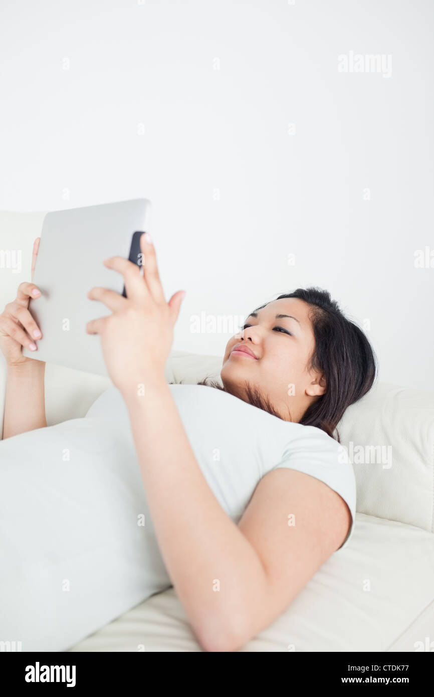 Woman lying on a sofa while holding a tactile tablet Stock Photo - Alamy