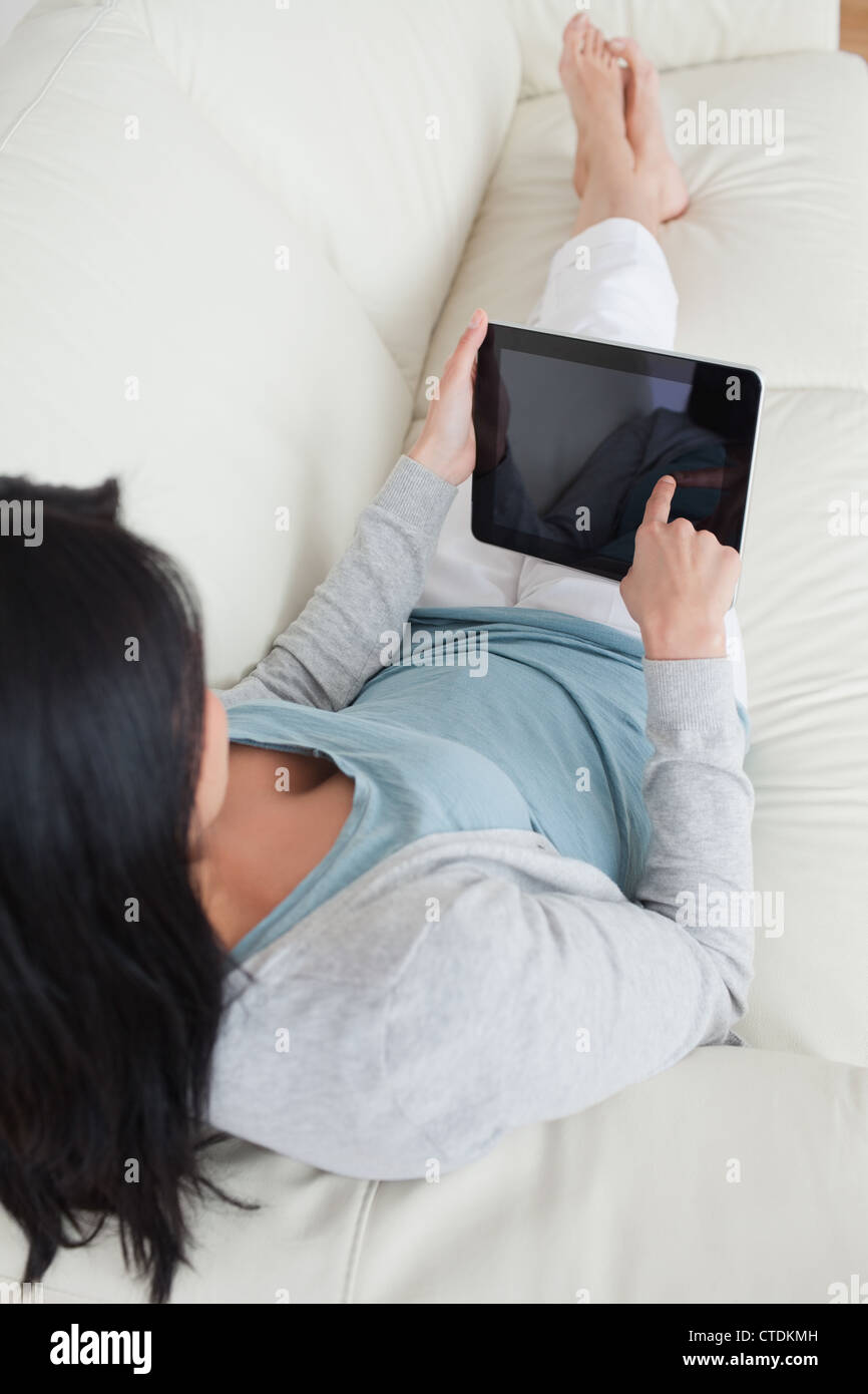 Woman lying on a sofa while touching a tactile tablet Stock Photo - Alamy