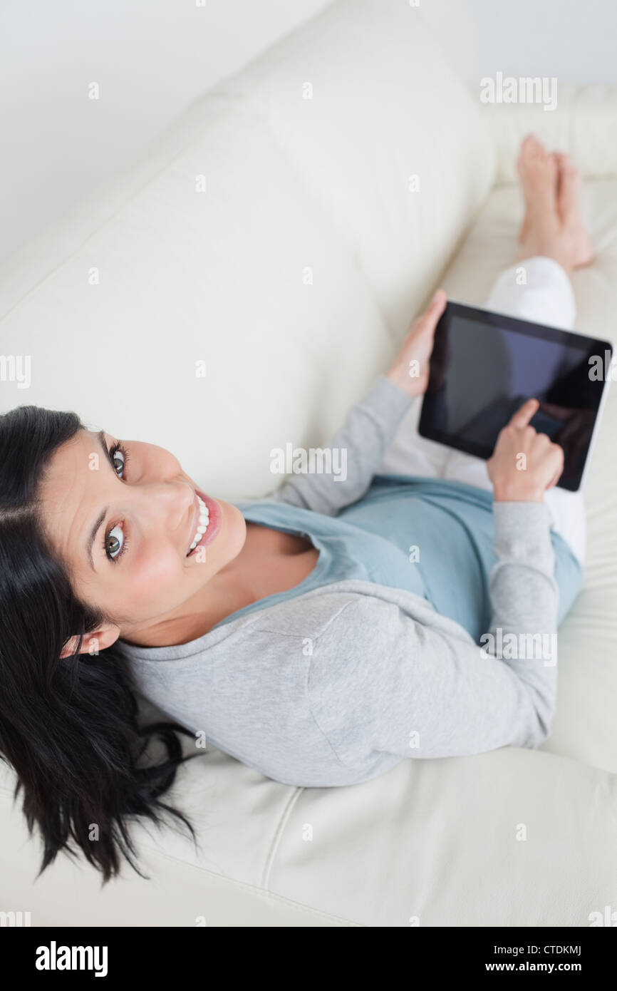 Woman relaxing on a sofa while touching a tablet Stock Photo - Alamy