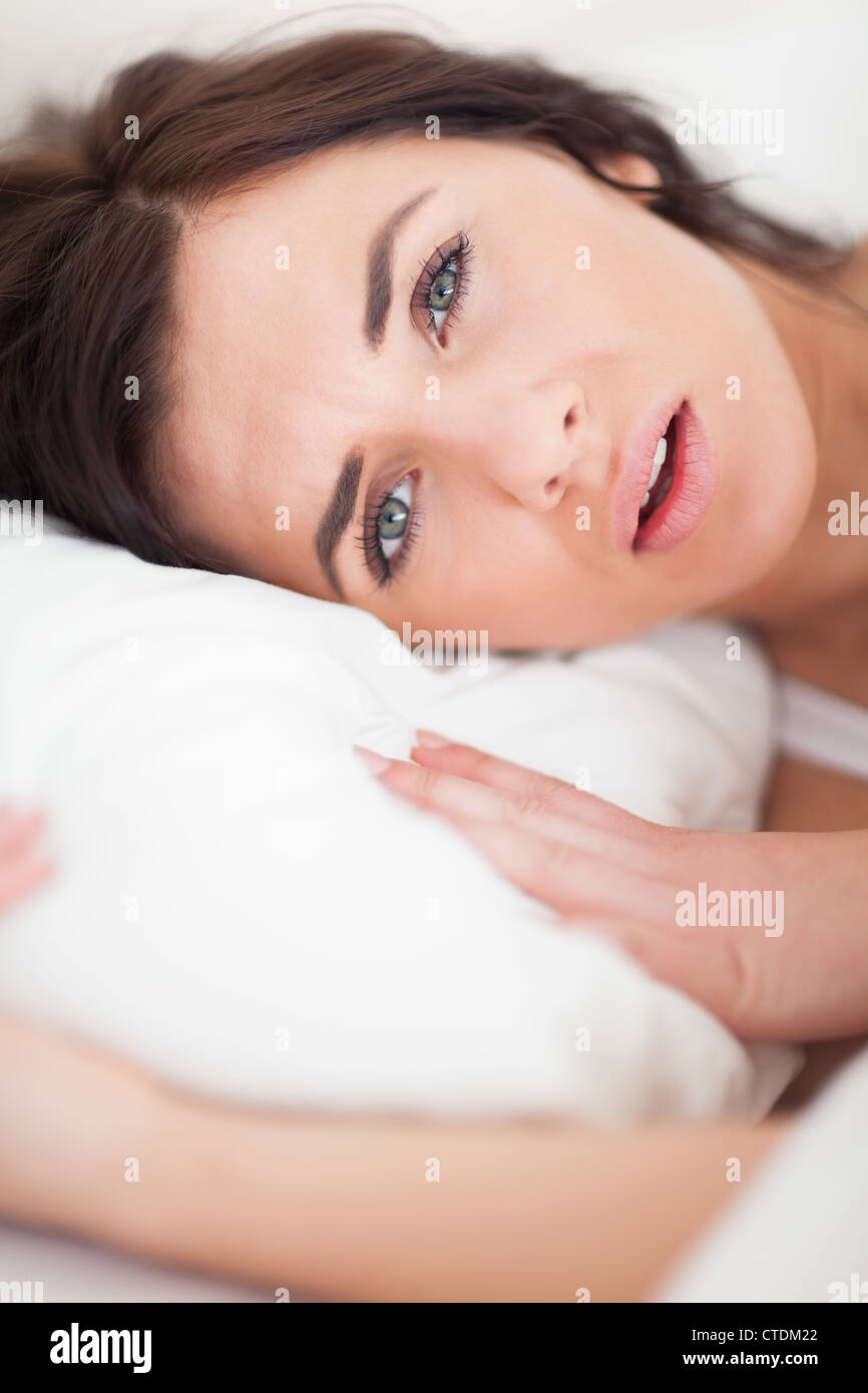 Brunette woman lying while placing her head on a pillow Stock Photo - Alamy