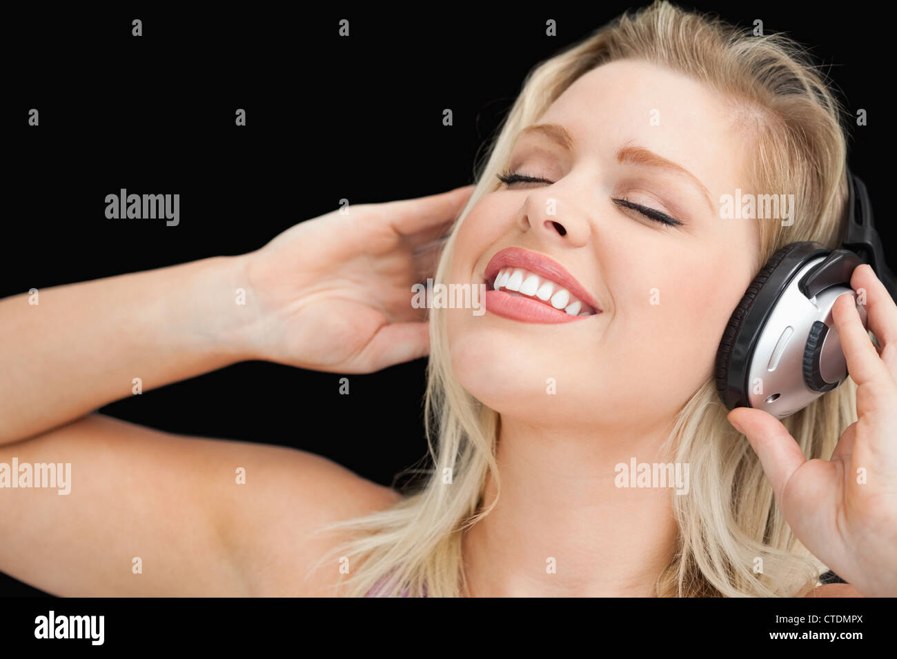 Joyful blonde woman listening to music through headphones Stock Photo