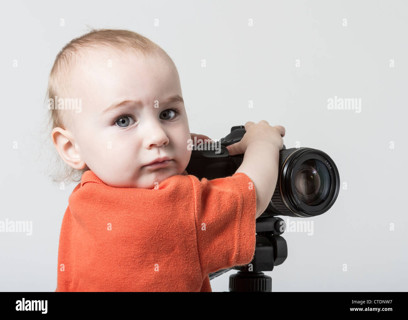 young child with digital SLR camera on grey background Stock Photo