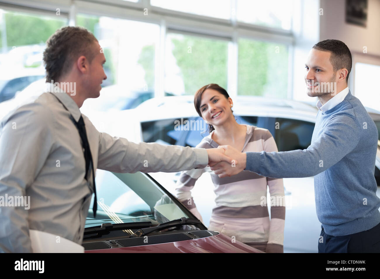 Car dealer shaking hand with a smiling man Stock Photo