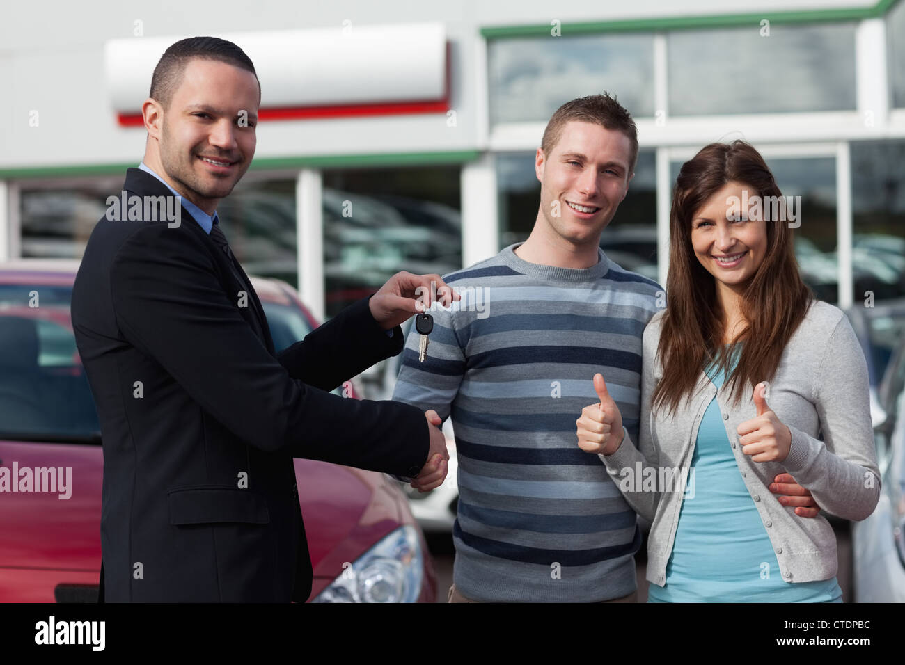 Dealer shaking hand of a man while giving him car keys Stock Photo