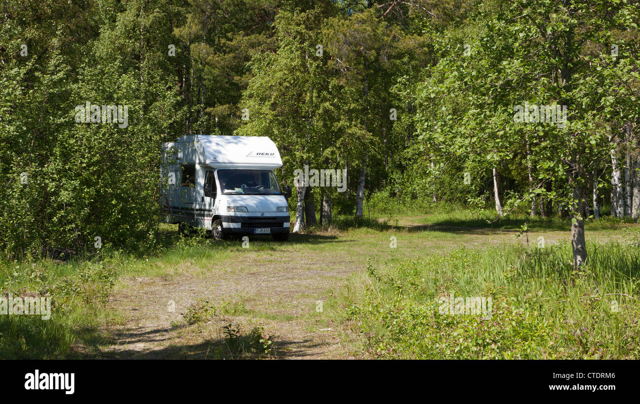 Camper standing in the shade of some trees in the midst of Finnish nature in summer Stock Photo