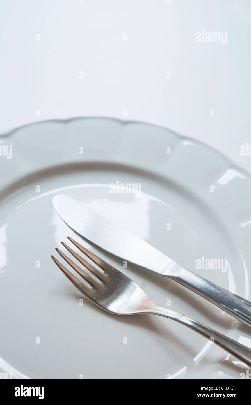 Fork and knife on an empty plate. Stock Photo