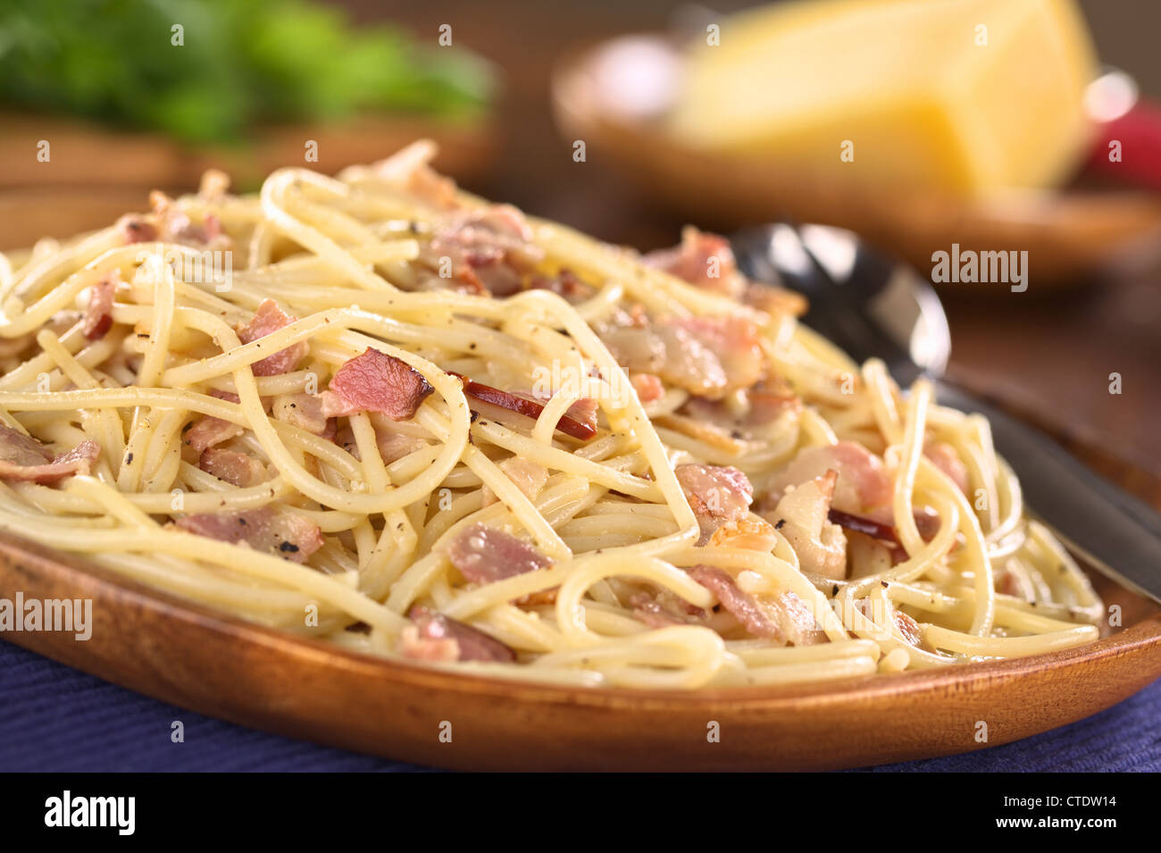 Spaghetti alla Carbonara served on wooden plate (Selective Focus, Focus one third into the meal) Stock Photo