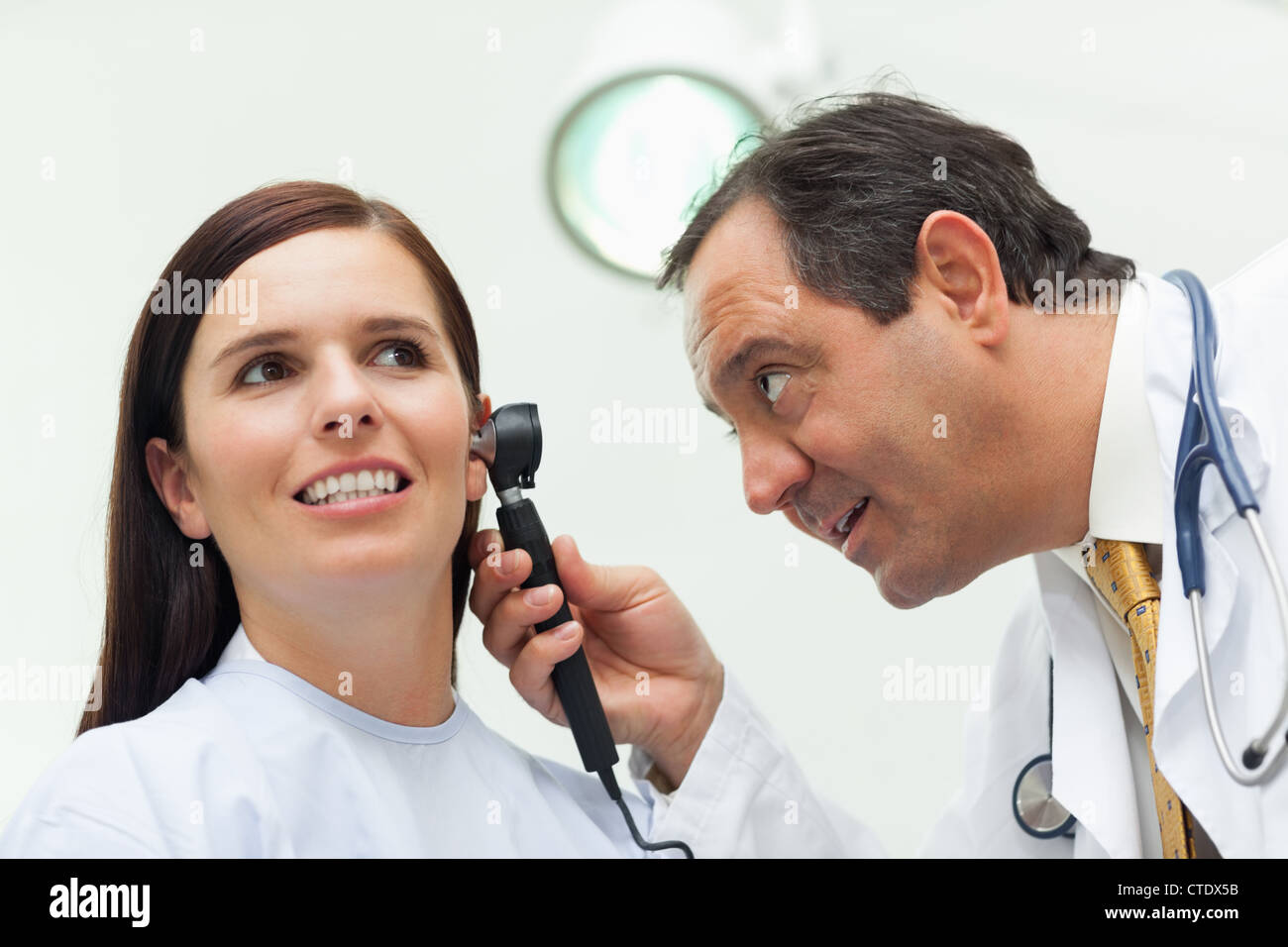 Doctor using an otoscope to look at the ear of his patient Stock Photo