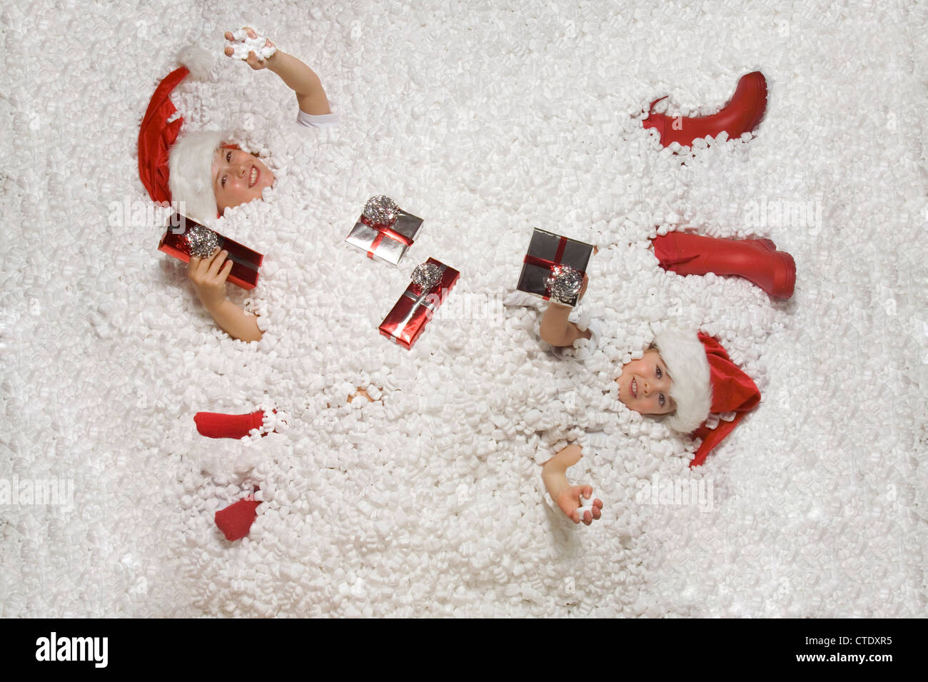 Christmas kids lay in snow with presents happy Stock Photo