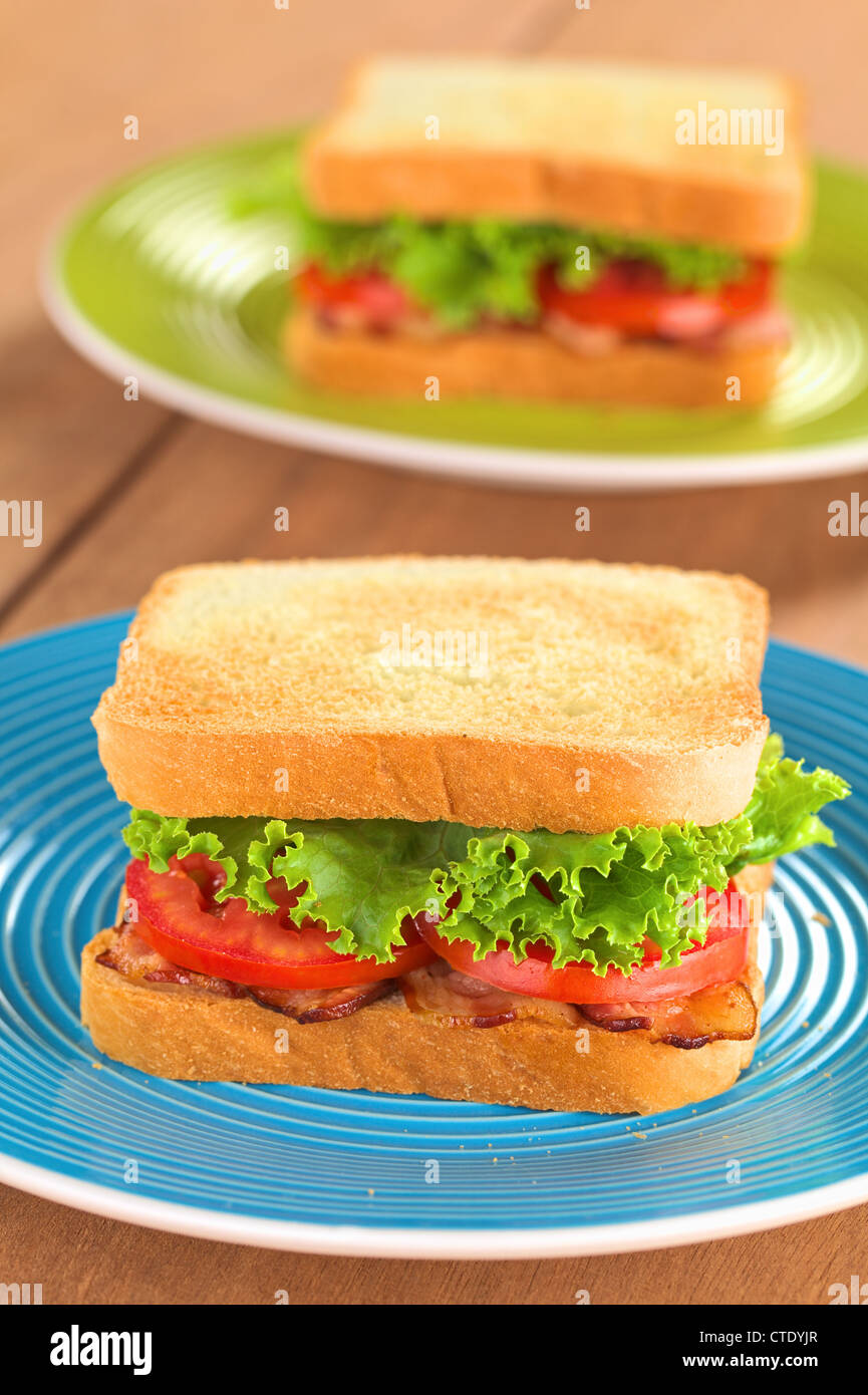 Fresh homemade BLT (bacon lettuce and tomato) sandwich on colorful plates Stock Photo