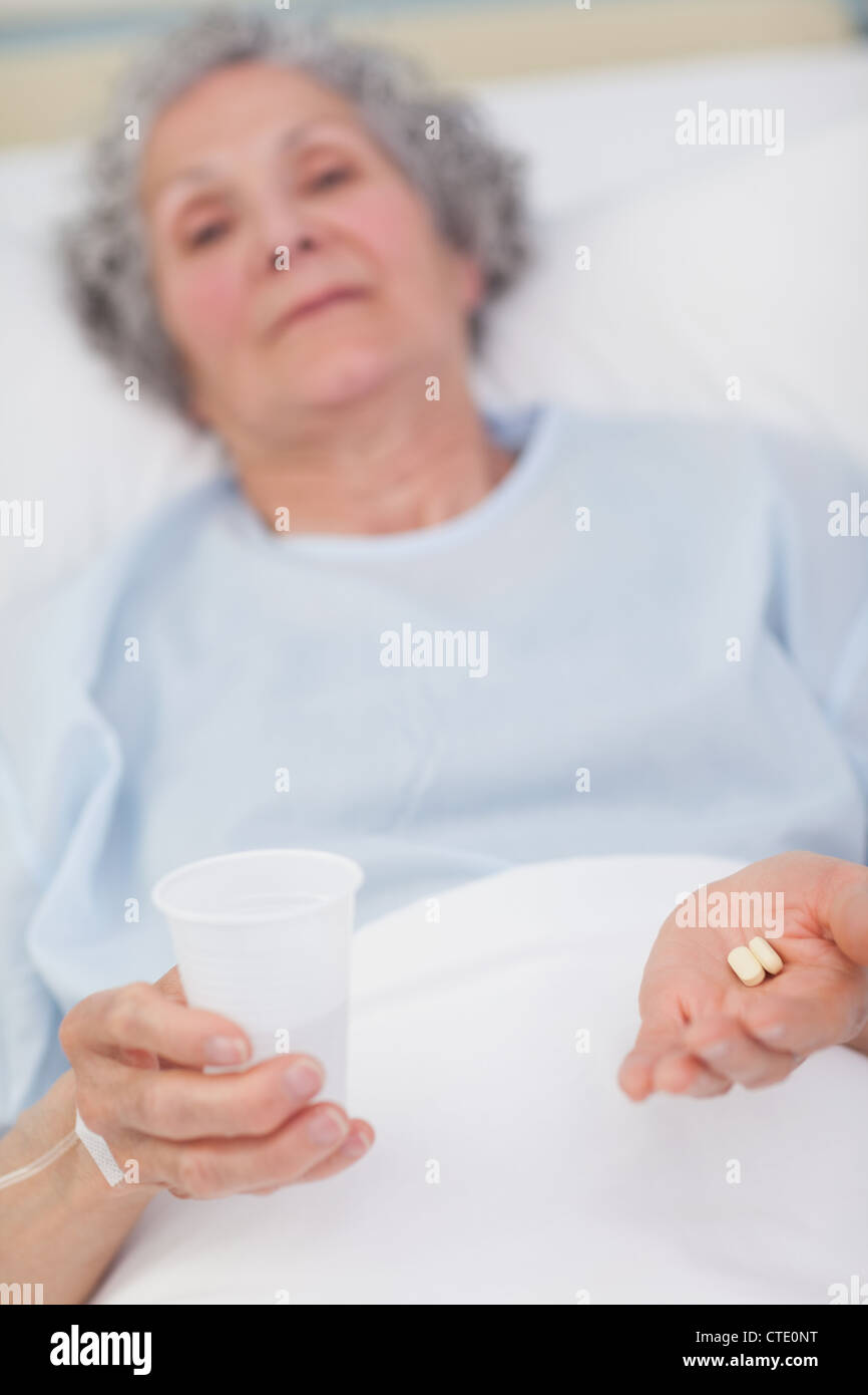 Patient holding drugs and plastic glass in her hands Stock Photo
