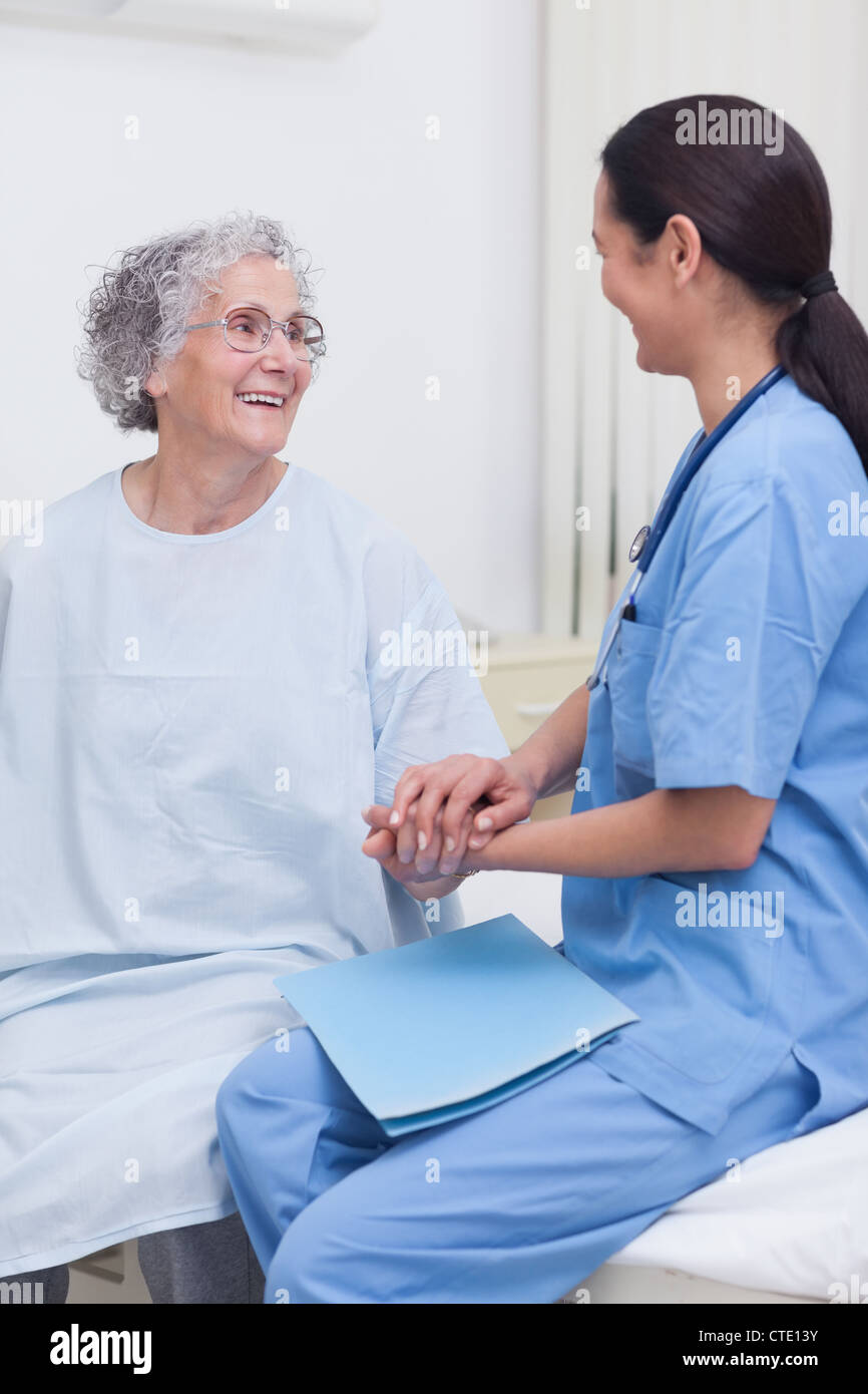 Nurse sitting on bed with a patient Stock Photo Alamy