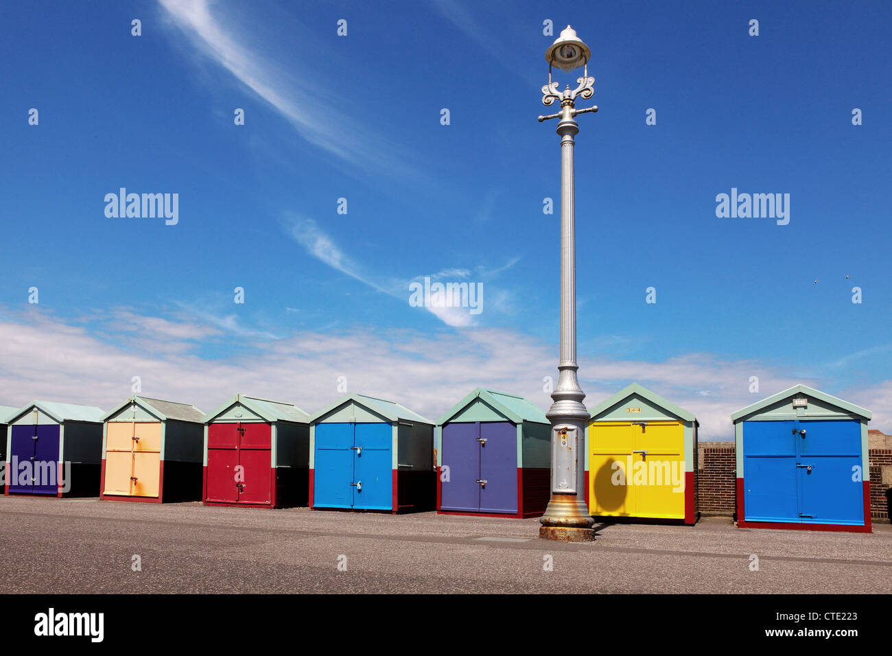 A row of beach huts with coloured doors and an old street lamp Stock Photo