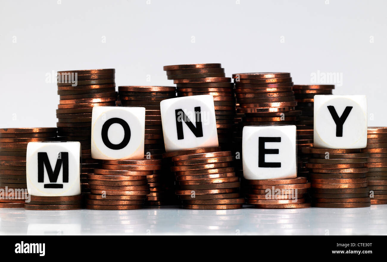 Dice balancing on a pile of coins, spelling out money Stock Photo