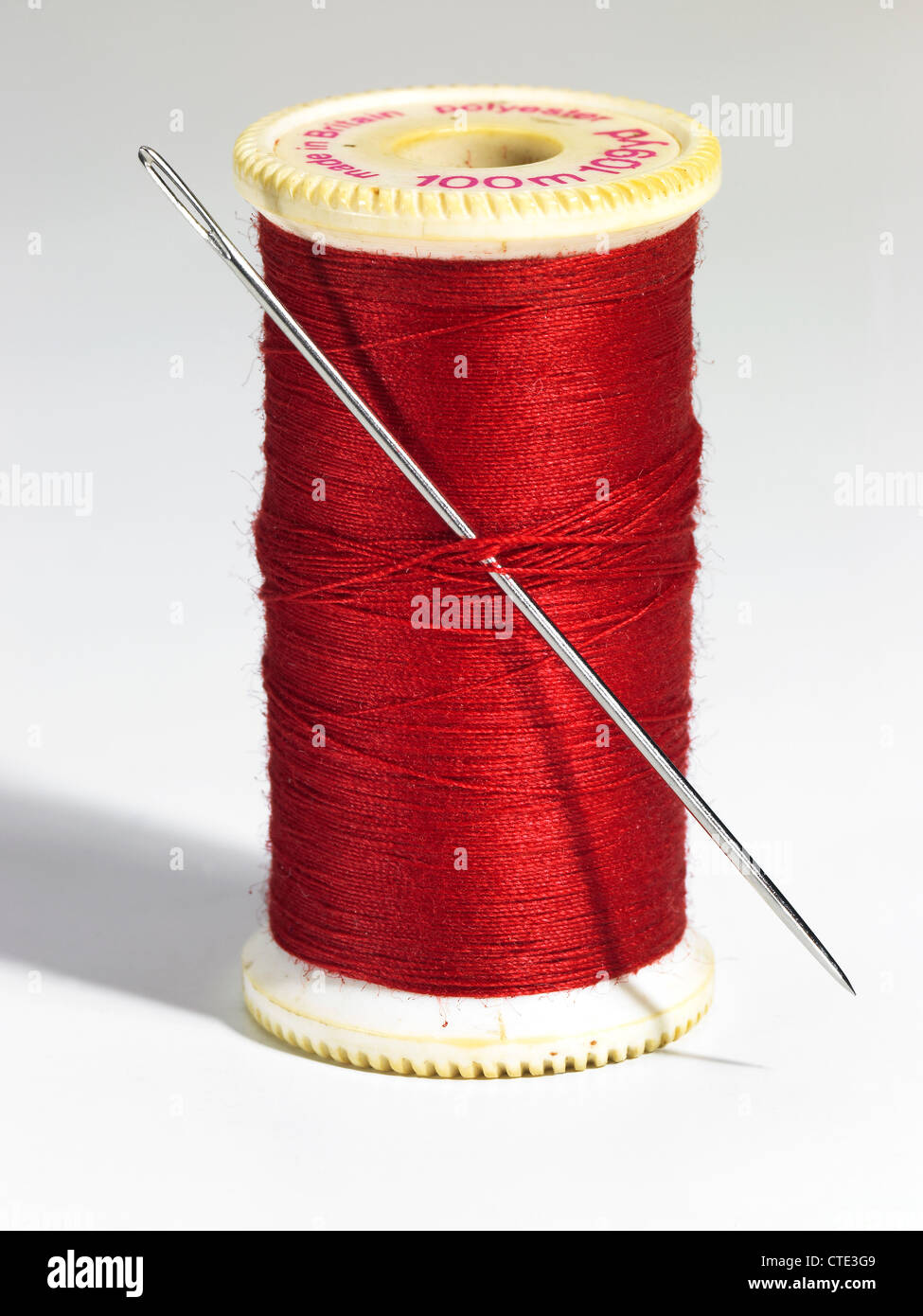 A reel of red cotton thread and a needle Stock Photo
