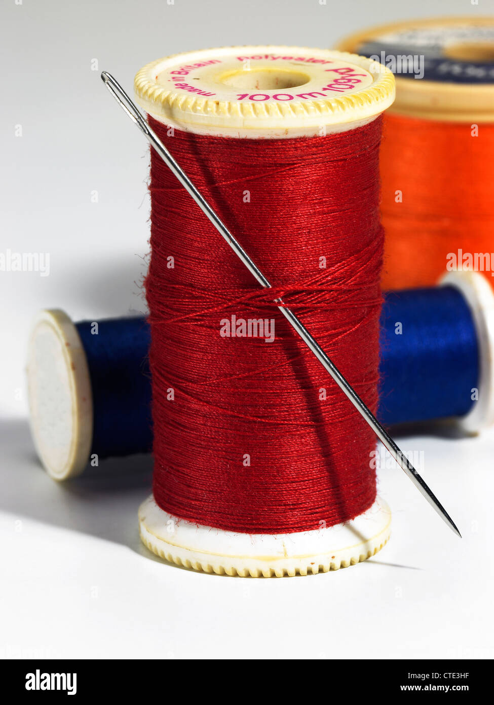 Reels of coloured cotton thread and a needle Stock Photo