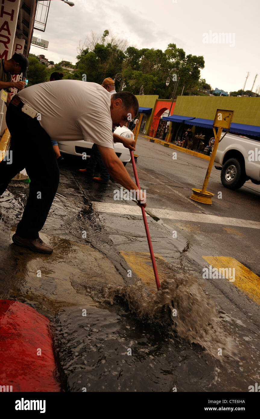 A man sweeps water from a street that was once busy with American tourists in Nogales, Sonora, Mexico. Stock Photo