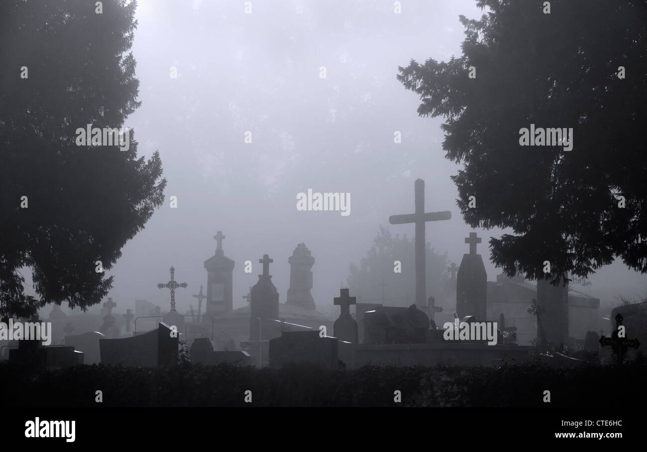 Eerie silhouetted tombstones, grisly graves and creepy crosses at ghastly graveyard with trees in foggy mist atmosphere Stock Photo