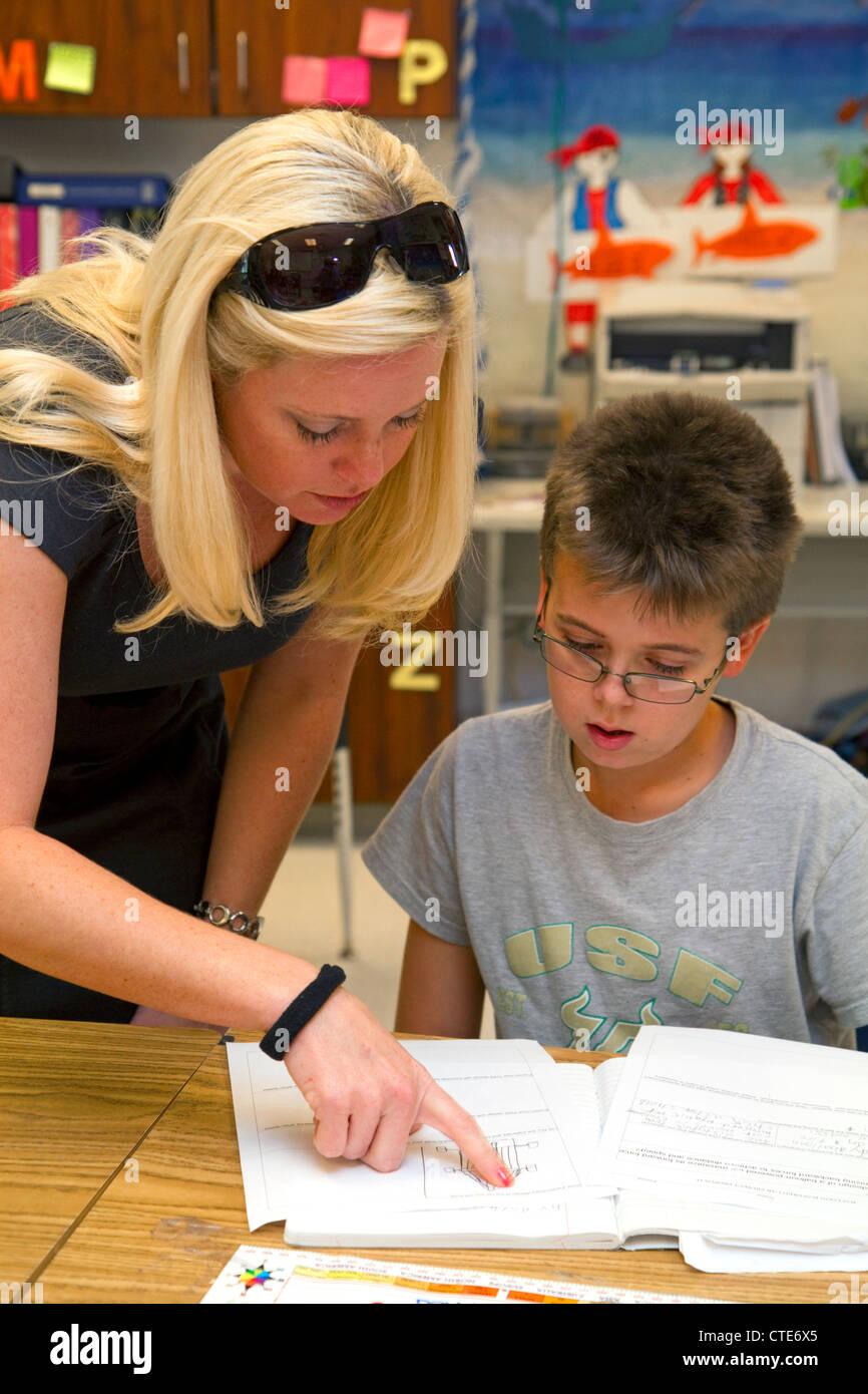 Female teacher helping students in a fourth grade classroom at a public elementary school in Brandon, Florida, USA. Stock Photo