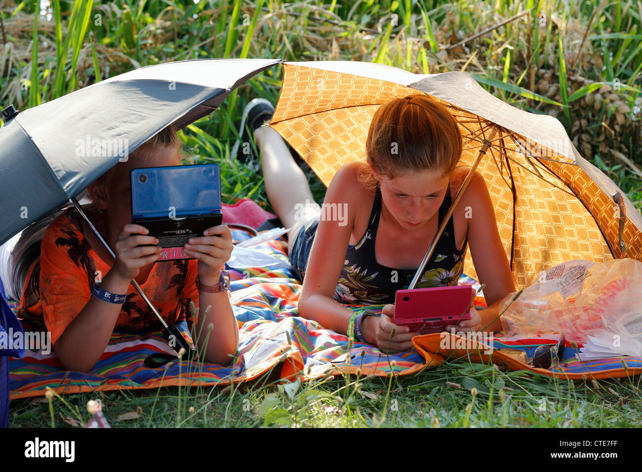 Girls playing portable video games under umbrellas in a city park, Boston, Massachusetts Stock Photo