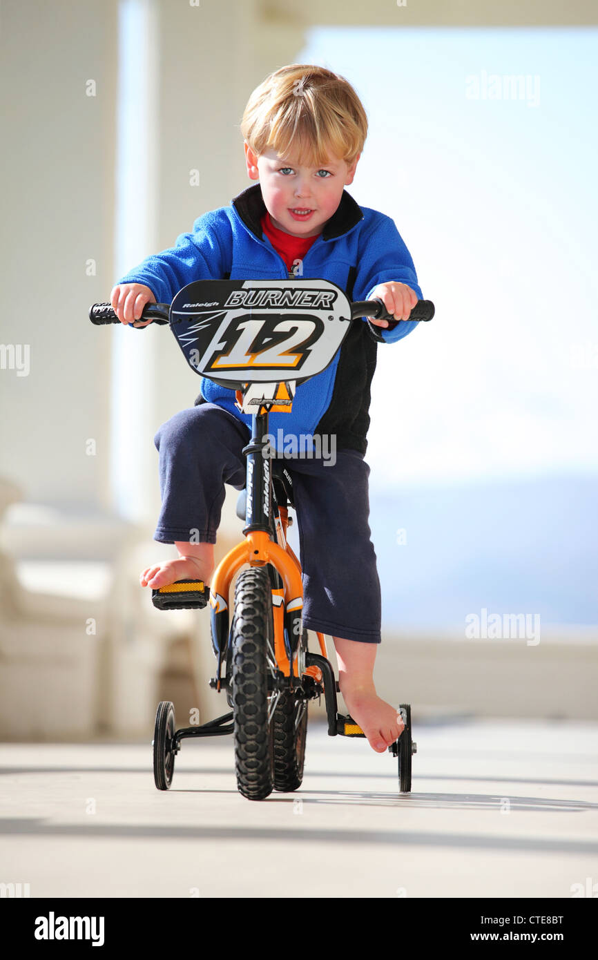 Young boy riding a bicycle with training wheels Stock Photo - Alamy