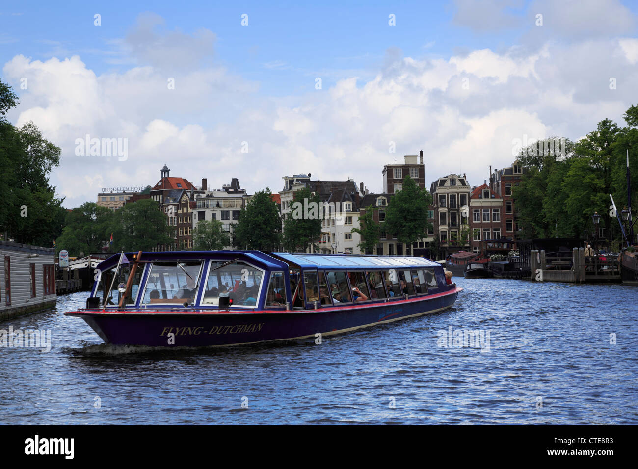 A covered tourist boat on the canals in Amsterdam. Stock Photo