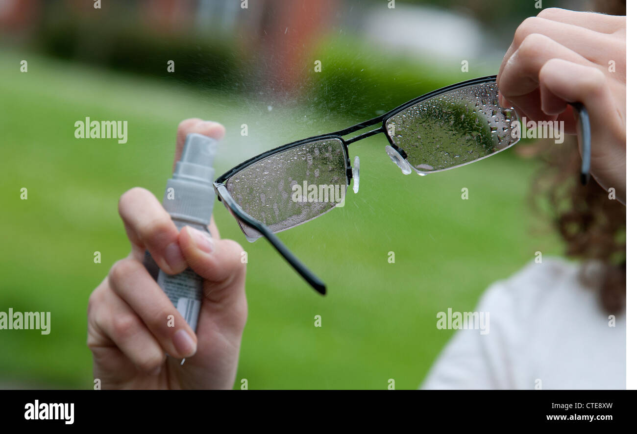 Cleaning spectacles with a spray on cleaner Stock Photo Alamy