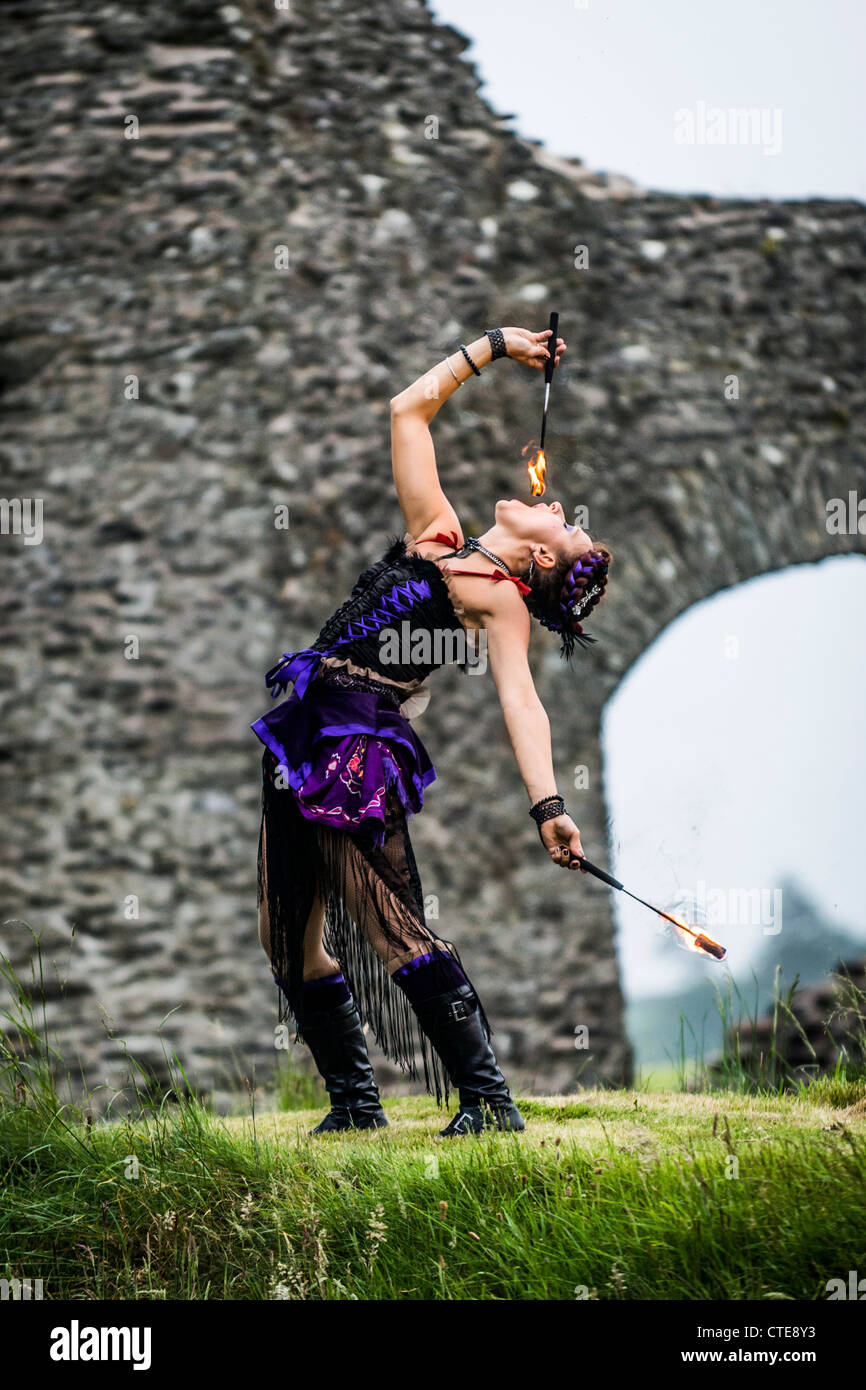 A woman circus performer bending backwards swallowing eating fire UK
