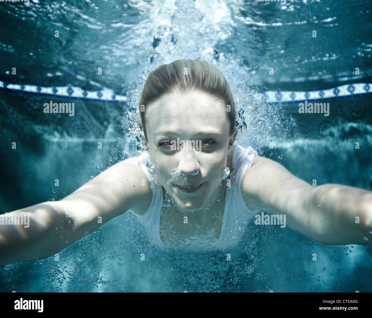 Girl swims towards camera after diving into a pool. Stock Photo