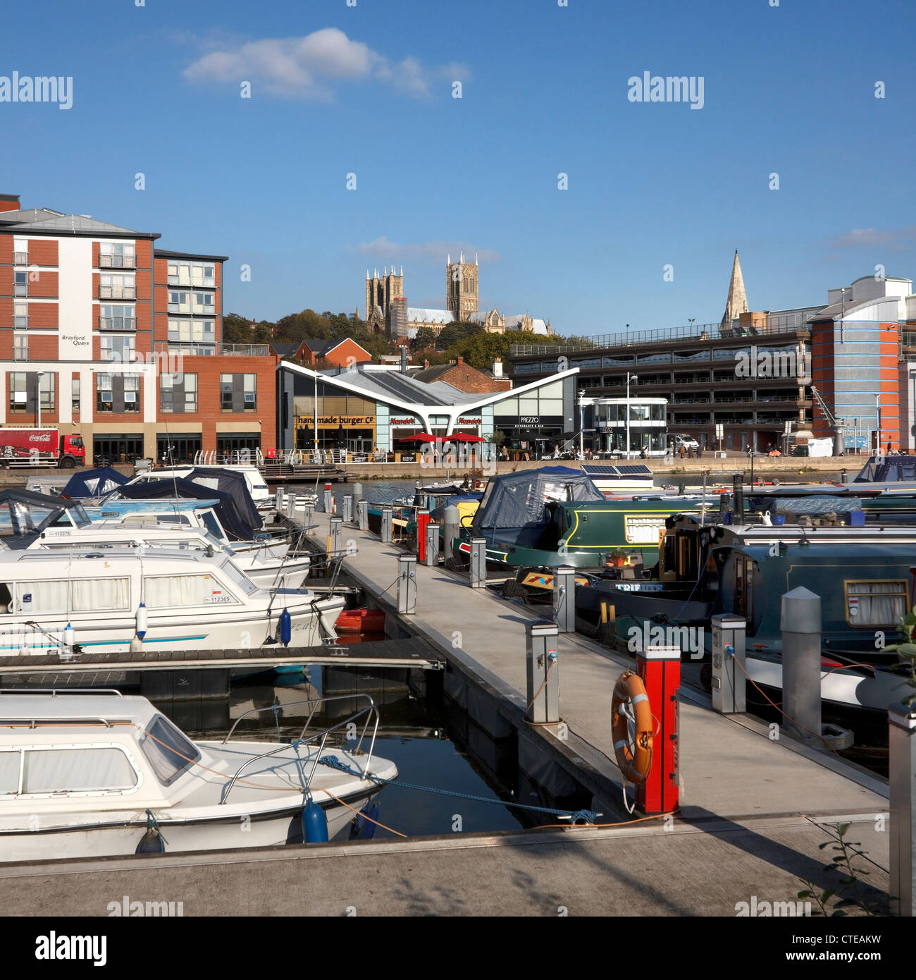 Boats and boardwalks in marina with shops and cathedral beyond at Brayford Waterfront, Lincoln City Centre, Lincolnshire, UK Stock Photo