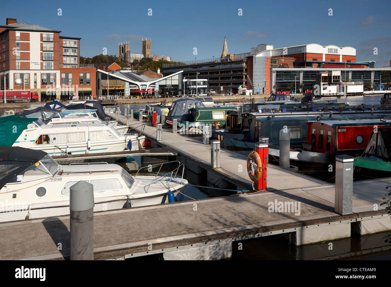 Boats and boardwalks in marina with shops and cathedral beyond at Brayford Waterfront, Lincoln City Centre, Lincolnshire, UK Stock Photo