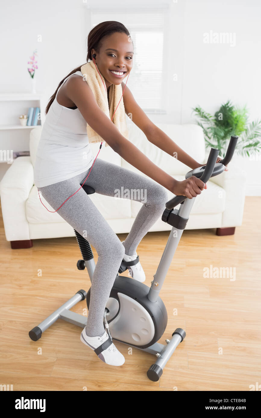 Black woman doing exercise bike with headphones Stock Photo