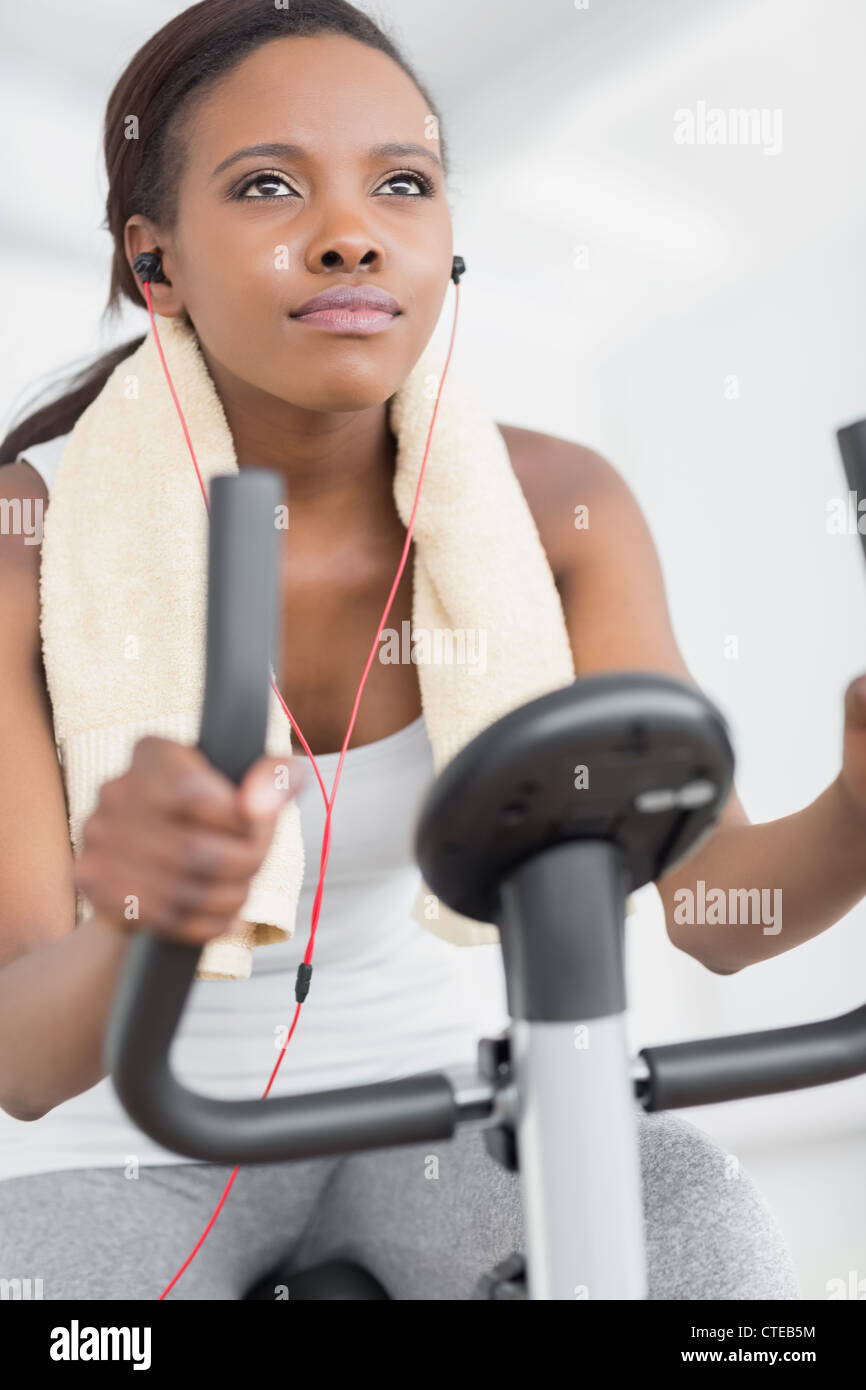 Concentrated woman doing exercise bike while listening music Stock Photo