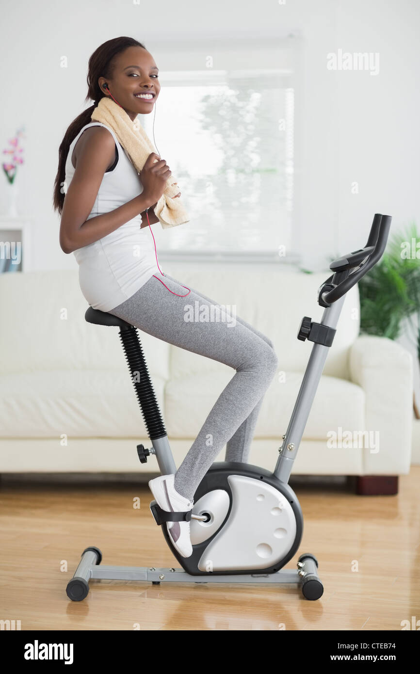 Black woman on an exercise bike smiling Stock Photo