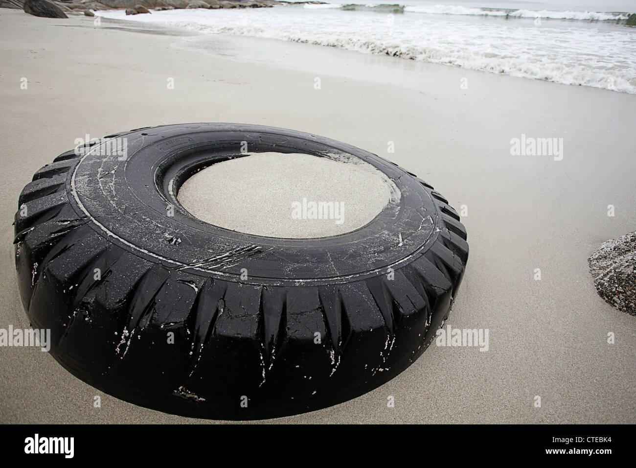 An abandoned tire lies littering the otherwise pristine beach Stock Photo
