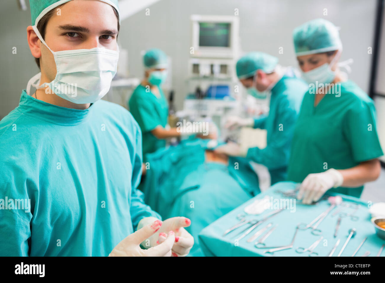 Surgeon wearing bloody gloves while looking at camera Stock Photo