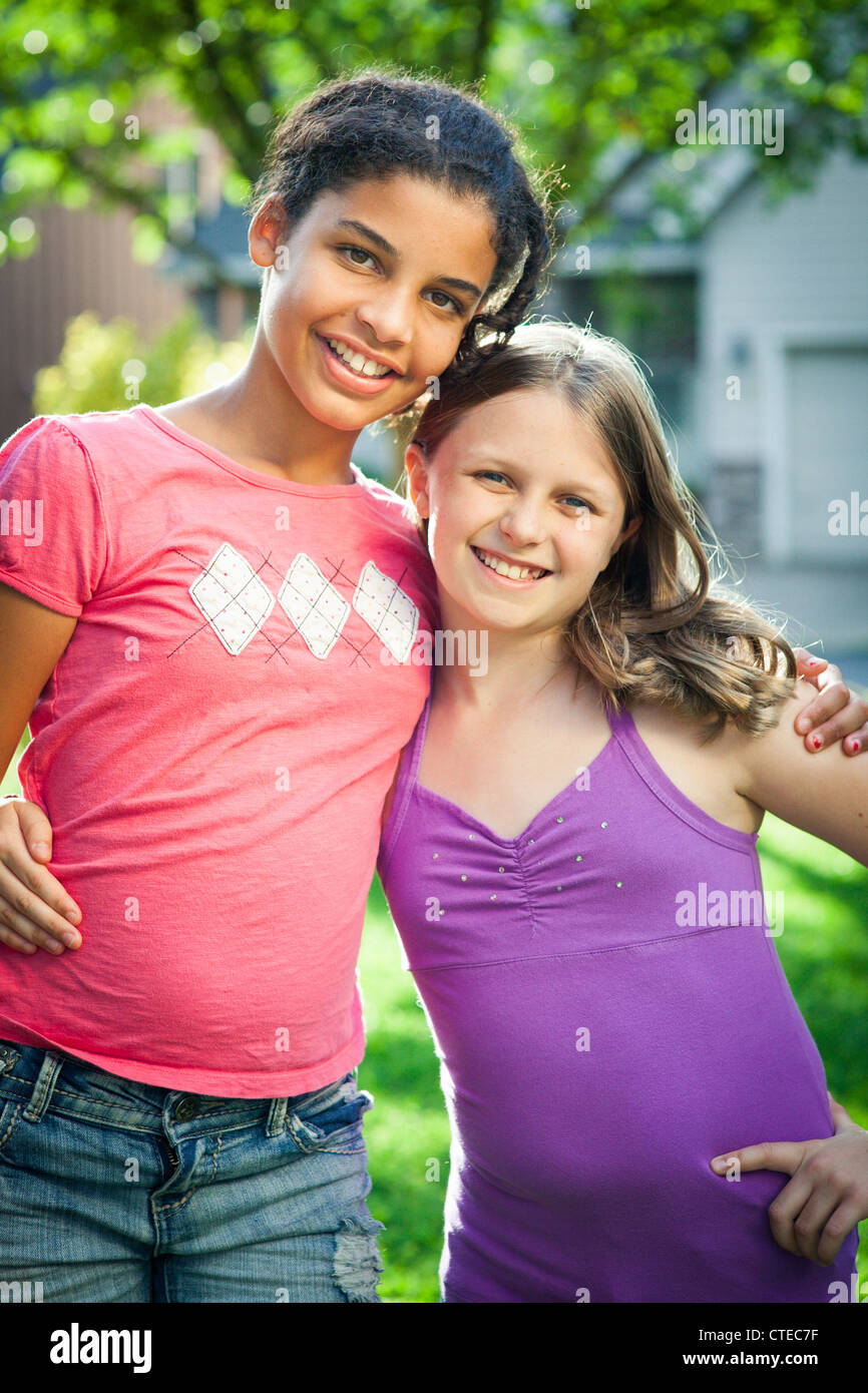 Two girls hug outdoors in the sunshine Stock Photo - Alamy