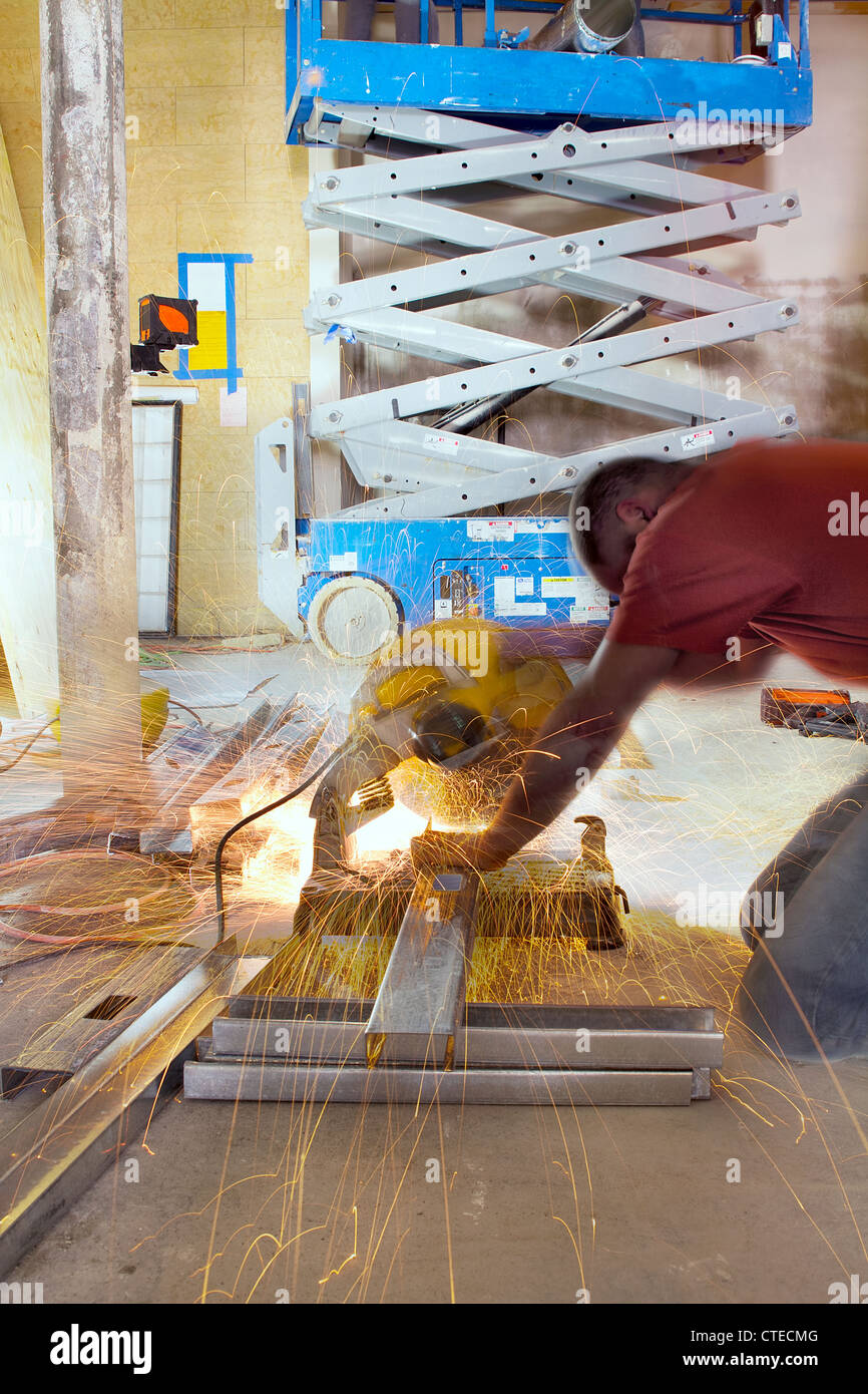 Construction Worker Cutting Metal Stud with Table Saw During Space Renovation Stock Photo