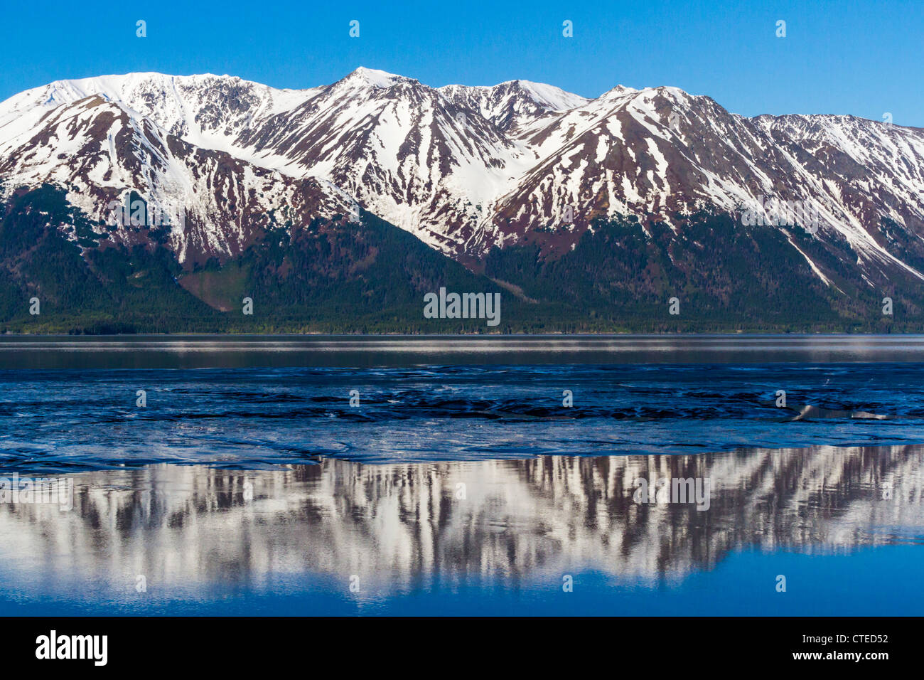 Reflections of snow-covered mountains in beautiful blue waters of 'Turnagain Arm,' an arm of 'Cook Inlet' in Alaska. Stock Photo