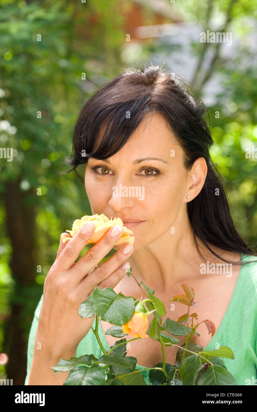 Woman in garden smelling rose Stock Photo - Alamy