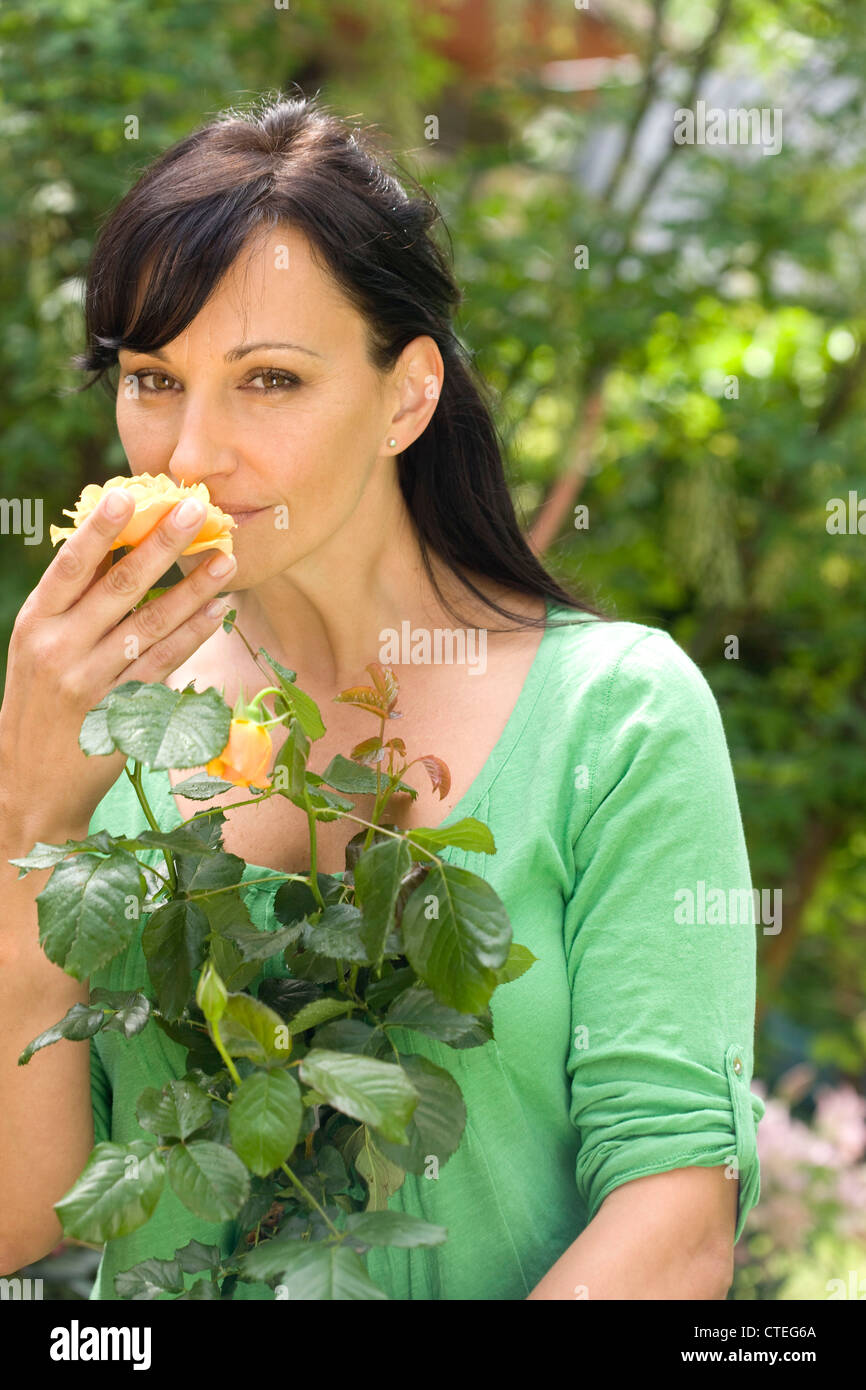 Woman in garden smelling rose Stock Photo - Alamy