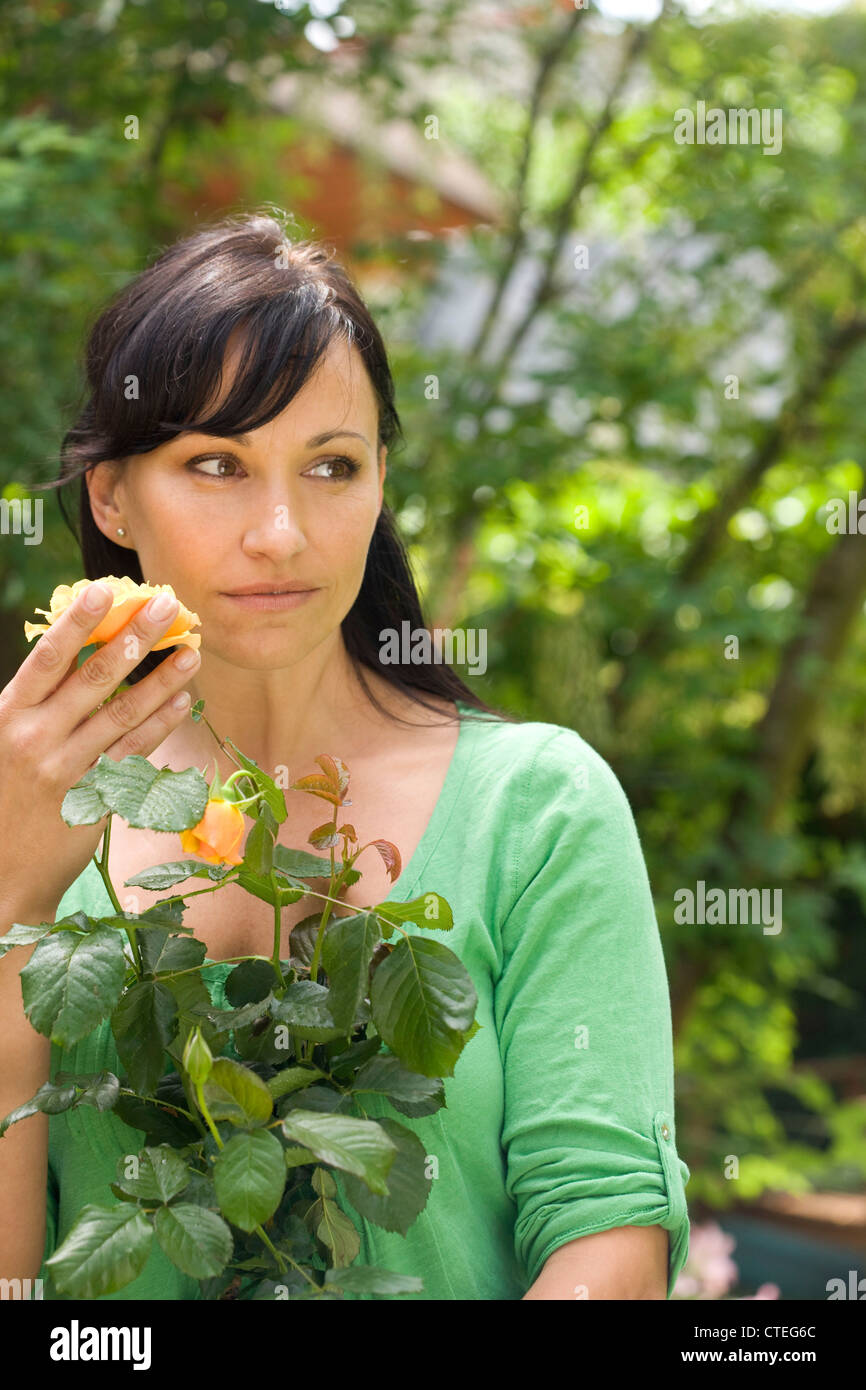Woman in garden smelling rose Stock Photo - Alamy