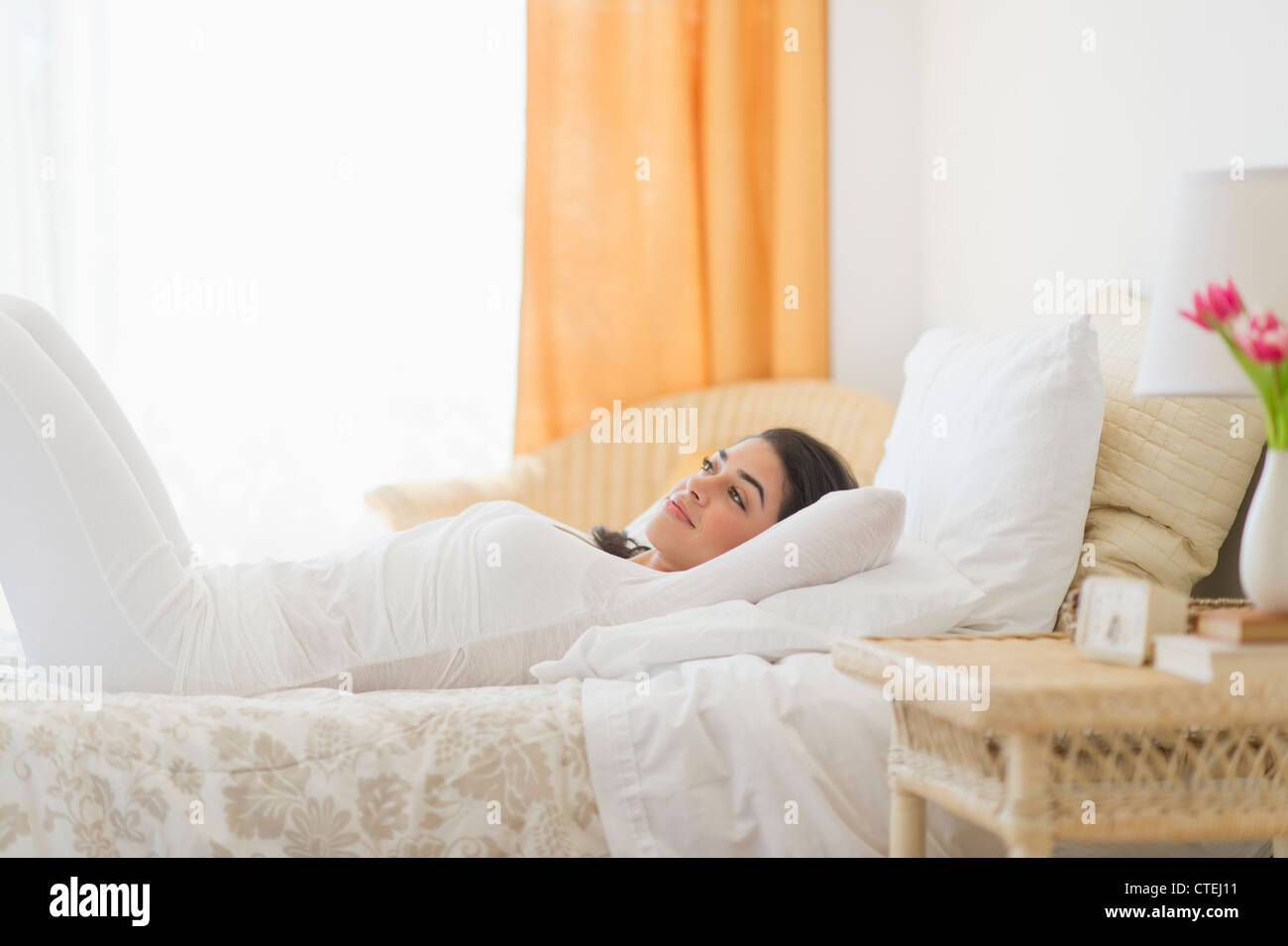 USA, New Jersey, Jersey City, Young woman lying on bed Stock Photo