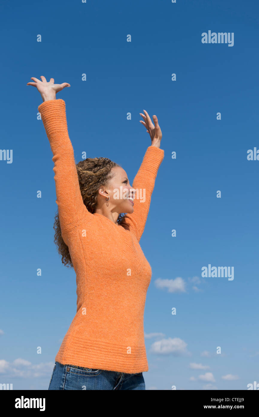 USA, New Jersey, Jersey City, Mature woman with arms raised towards blue sky Stock Photo